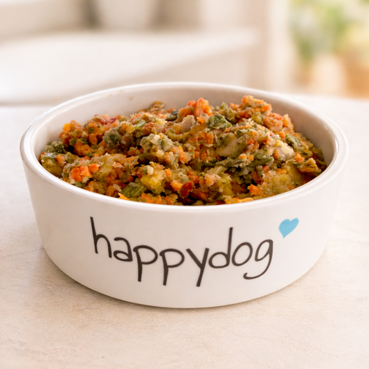 White bowl of dog food with 'happydog' branding on a light surface.